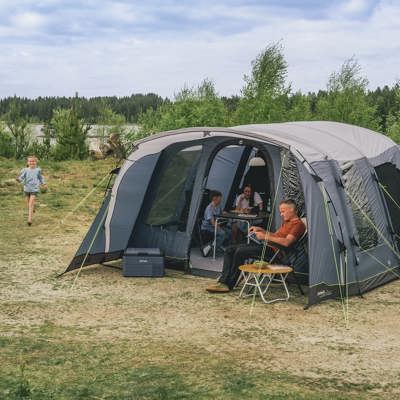 På billedet ses en familie på campingtur i et telt fra Outwell. Familien hygger sig med fælles aktiviteter og afslapning.