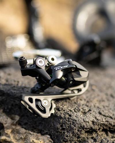 Billedet viser en bagskifter fra Shimano 105 på en flot grafisk baggrund.
