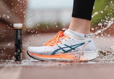 Billedet viser et rør med PurePower Hydro tabs. Billedet er et livsstilsbillede med en løbesko der træder i en vandpyt.