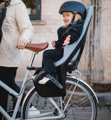 billedet viser en glad dreng der sidder i en cykelstol og nyder omgivelserne.